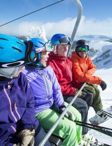 Three people on a chair lift for a ski mountain